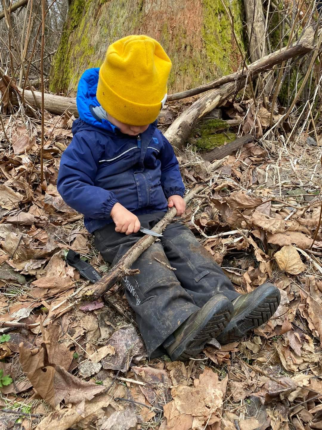 小さな男の子が地面に座りナイフを使うようす。リスキープレイを行うようすを表す